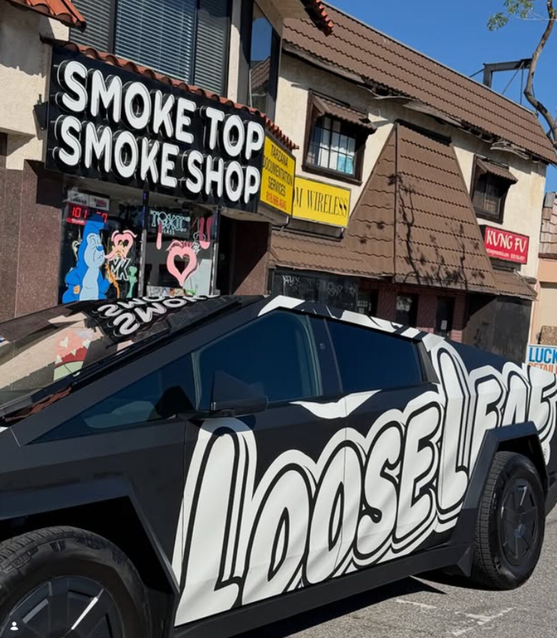 The Smoke Top Smoke Shop storefront on Ventura Blvd in Tarzana, with a black and white bubble letter sign above the door and a wrapped truck parked out front